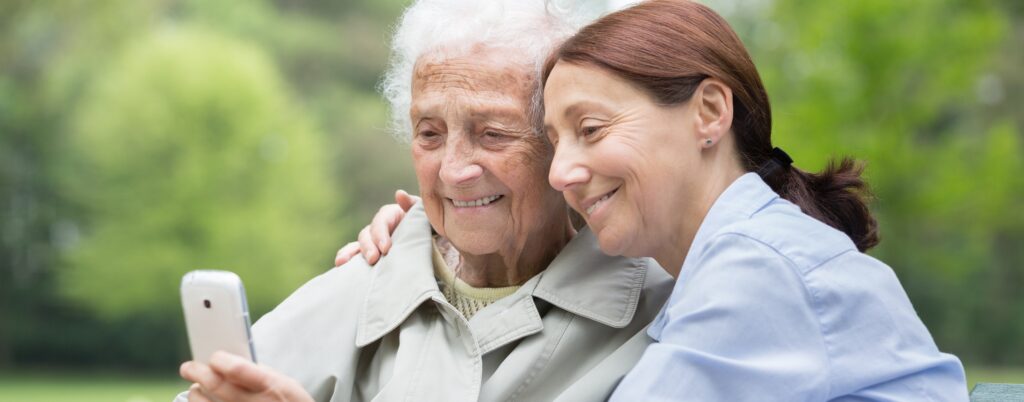 Caregiver helping an elderly woman make a call