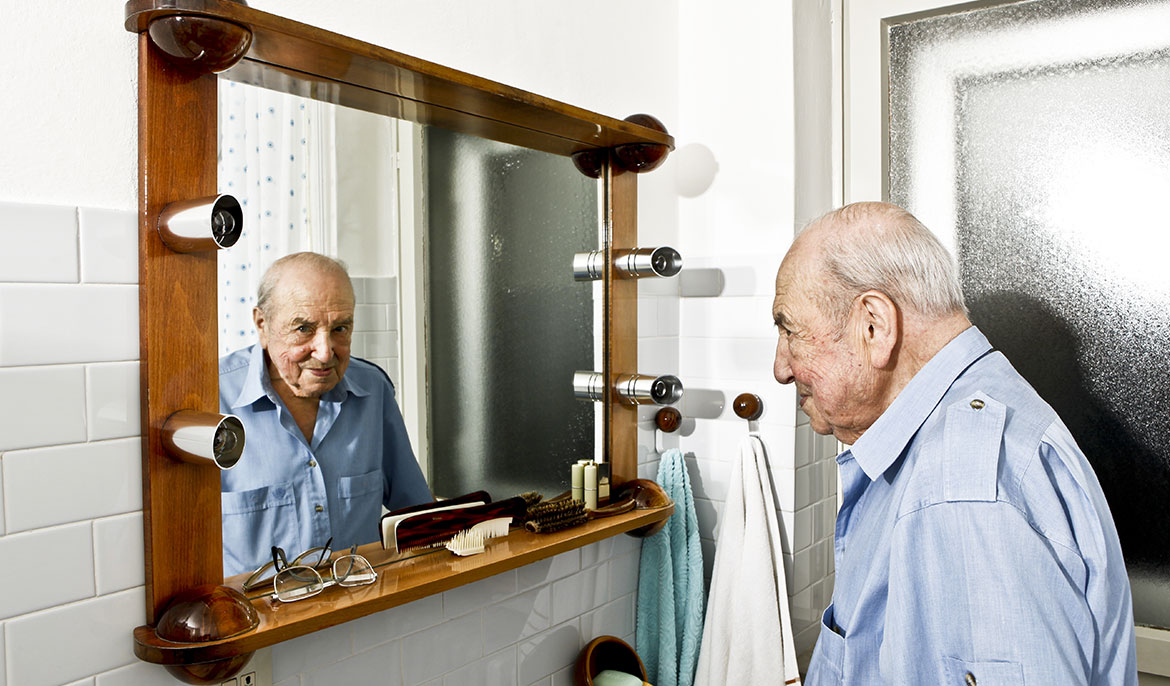 An elderly man looking into the mirror