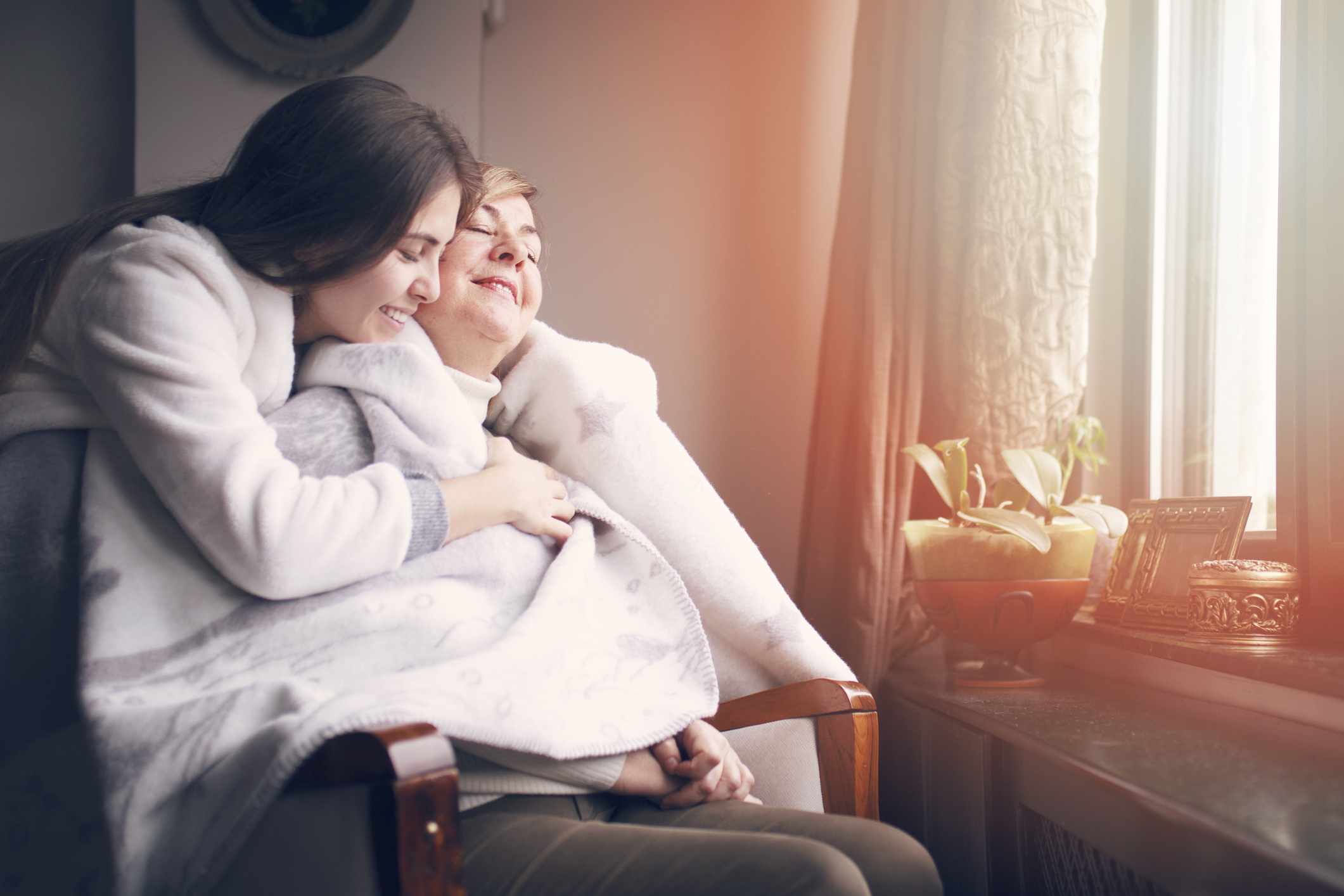 A young woman wrapping an older woman in a blanket