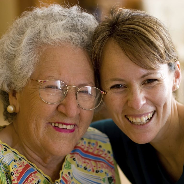 Healthcare worker hugging an elderly woman