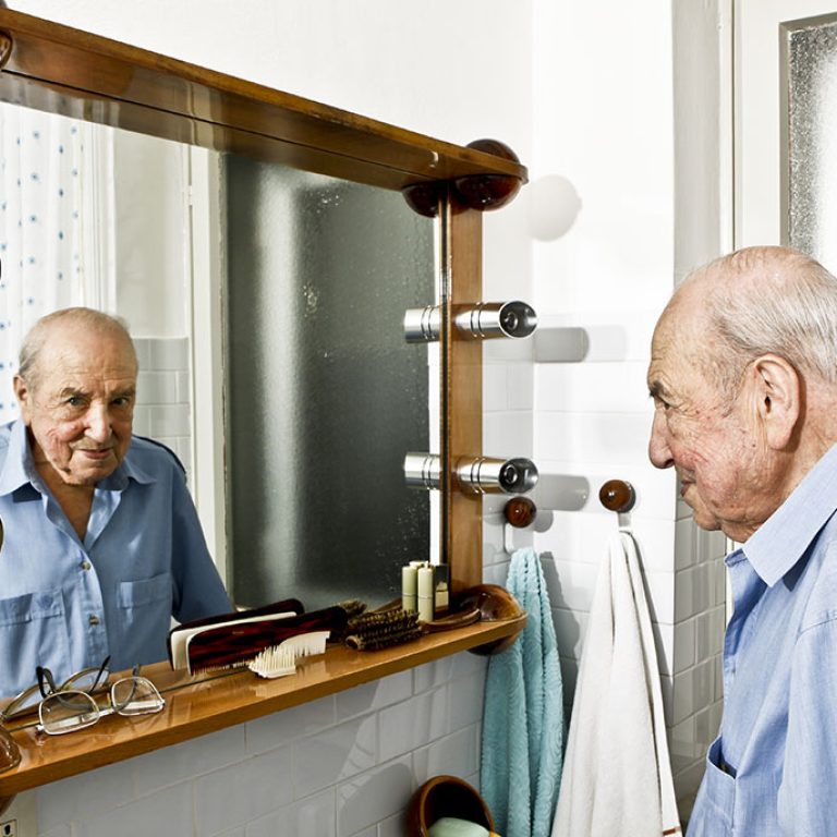 An elderly man looking into the mirror